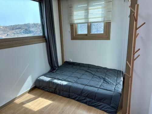 a small bed in a room with a window at Fullhouse 6TO10 in Gangneung