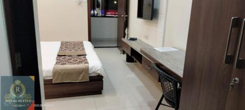 a small room with a bed and a desk at Royal Suites in Pune