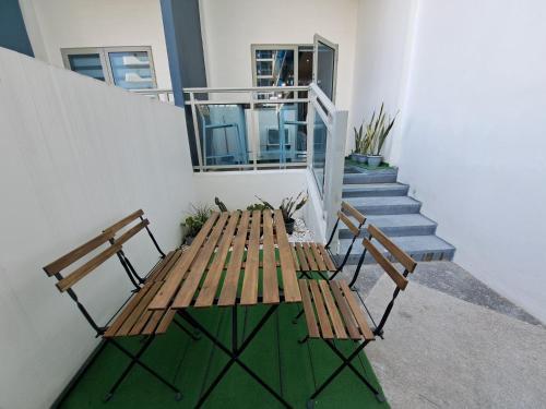 two wooden benches sitting next to a building with stairs at Hailey's Crib @ Azure North in San Fernando