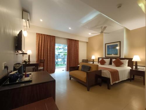 a hotel room with a bed and a chair at Kyriad Prestige Calangute Goa by OTHPL in Calangute