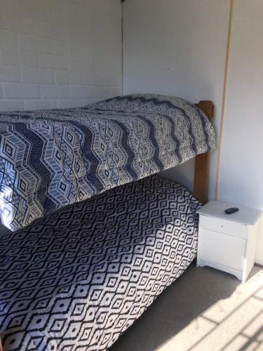 ein Bett mit einer Decke und ein Nachttisch daneben in der Unterkunft Tu espacio Re - Cuarto descanso in Santiago