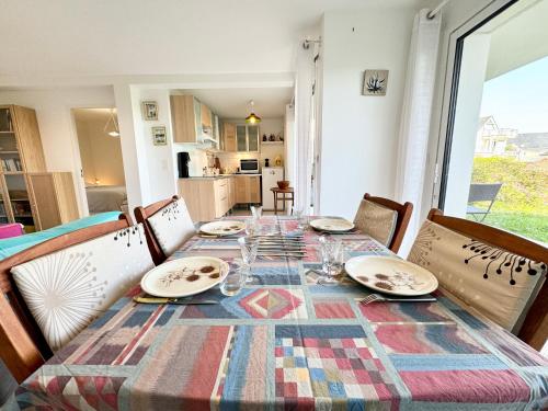 una mesa de comedor con platos y vasos. en Bel appartement face à la mer - Terrasse et jardin, en Larmor-Plage