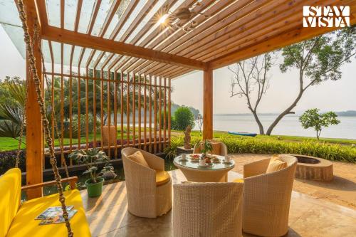 a patio with a swing and a table and chairs at StayVista at Exotica Kabini - All Meals Included in Antarasante