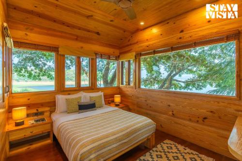 a bedroom with a bed in a log cabin at StayVista at Exotica Kabini - All Meals Included in Antarasante