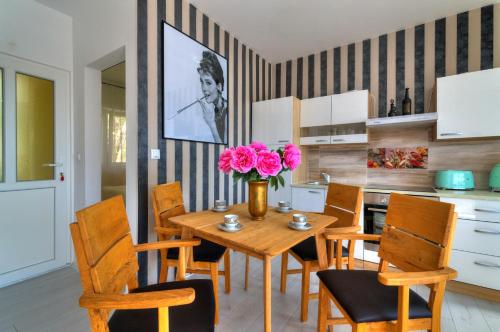 a dining room with a wooden table with pink flowers at Casa Memory in Crikvenica
