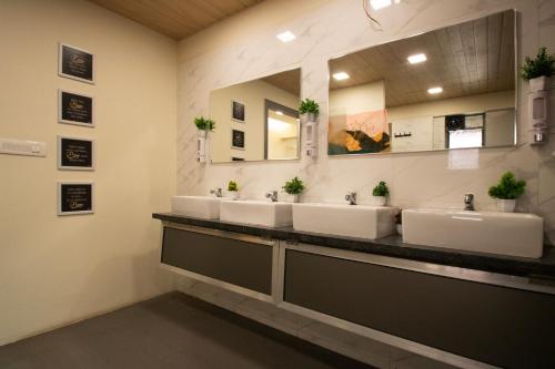 a bathroom with three sinks and a large mirror at Hostells in Pune