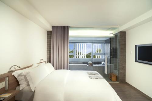 a bedroom with a white bed and a bathroom at Just Sleep Jiao Xi in Jiaoxi