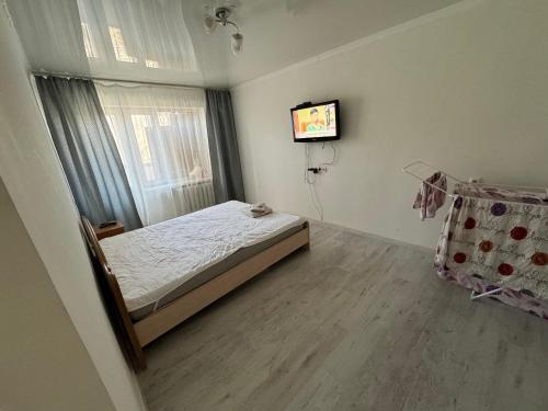 - une chambre avec un lit et une télévision murale dans l'établissement Сдается уютная 1 комнатная квартира, à Astana