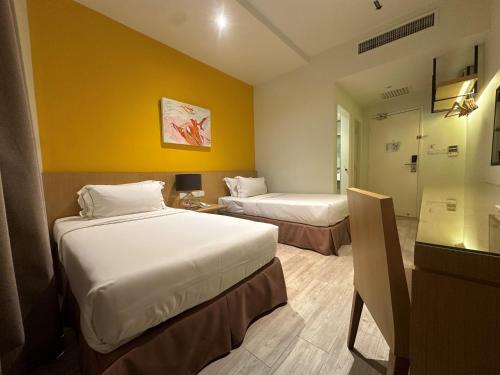 two beds in a hotel room with yellow walls at SGI Vacation Club Hotel in Melaka