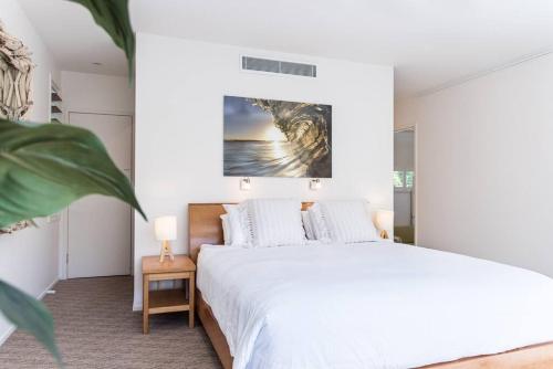 a white bedroom with a bed and a painting on the wall at Villa Ohana Pono Luxury Family Home in Sunshine in Sunshine Beach