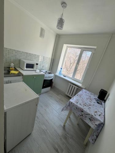 uma pequena cozinha com uma mesa e uma janela em Сдается уютная 1 комнатная квартира em Astana