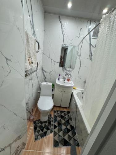 La salle de bains est pourvue de toilettes, d'un lavabo et d'une baignoire. dans l'établissement Сдается уютная 1 комнатная квартира, à Astana