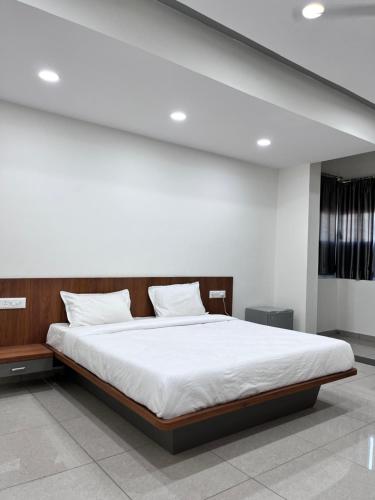 Hālol的住宿－HOTEL KANHA INN，一间卧室配有一张带白色床单的大床
