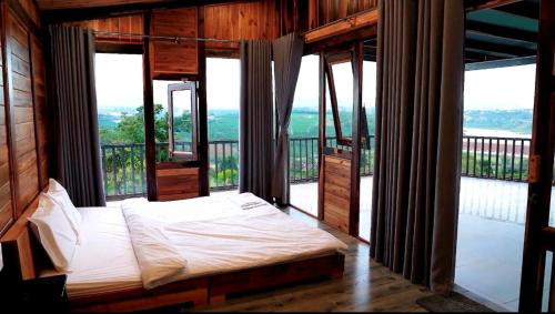 a bedroom with a bed in a room with windows at KMI Homestay – Tea and Coffee in Di Linh