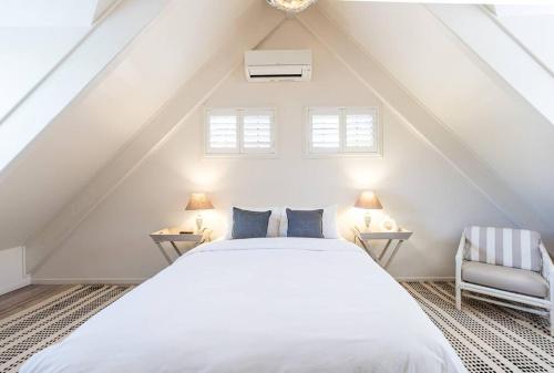 a bedroom with a white bed and two chairs at The Rest Family Cottage with Resort Style Pool in Noosa Heads