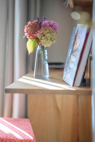 a vase of flowers on a table next to a book at Biohotel Garmischer Hof in Garmisch-Partenkirchen