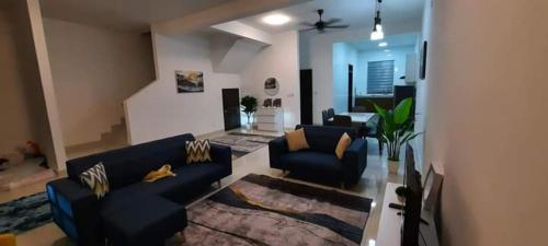 Una sala de estar con dos sofás azules y una alfombra. en D'Aster Sara's Homestay Seremban NS, en Seremban