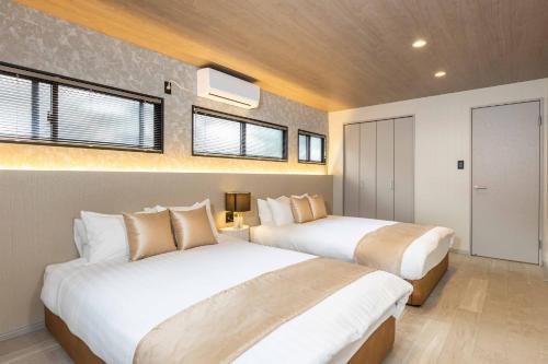 two beds in a bedroom with two windows at JAPAVISTA Aqua in Osaka