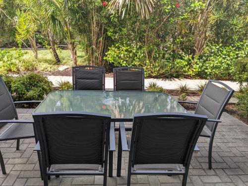 C Mandurah Apartment Resort في ماندورا: طاولة زجاجية حولها اربعة كراسي