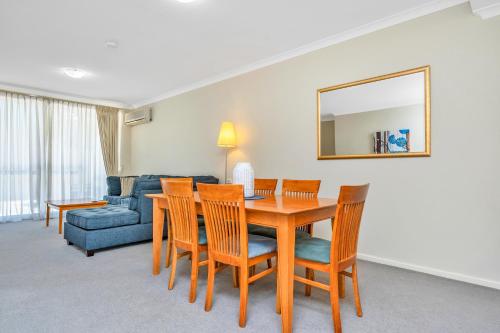 a dining room with a table and chairs and a couch at C Mandurah Apartment Resort in Mandurah