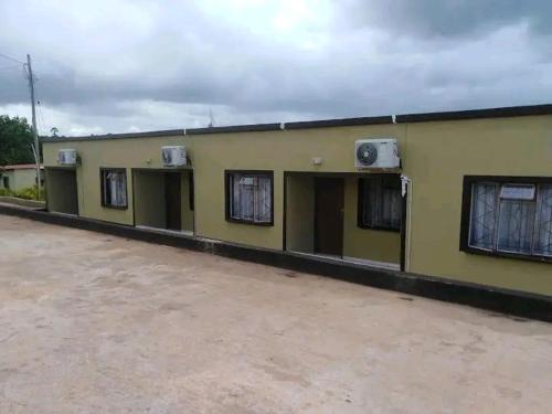 ein gelbes Gebäude mit Fenstern und Klimaanlagen daran in der Unterkunft Rest Camp Lodge in Manzini