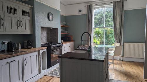 a kitchen with white cabinets and a large window at Spacious home, by Headingley Stadium, LGI, Leeds Arena, and the University of Leeds in Headingley