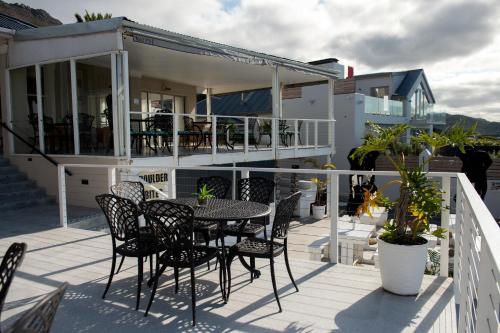 a patio with a table and chairs on a balcony at Boulders Beach Hotel, Cafe and Curio shop in Simonʼs Town