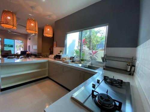 a kitchen with a stove and a sink and a window at The Fint Hus Villa Langkawi in Pantai Cenang