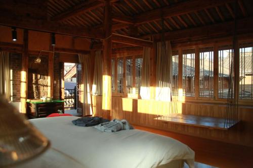 a bedroom with a bed in a room with windows at Playing Again Hostel in Lijiang