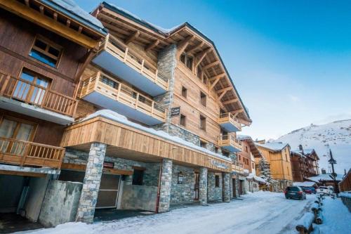 ein großes Holzgebäude mit Schnee auf dem Boden in der Unterkunft Residence Cap Neige in Tignes