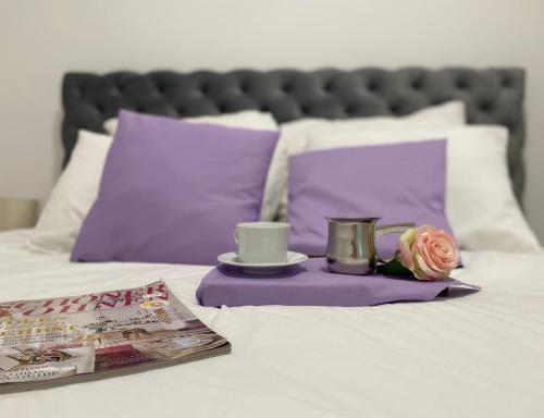 a tray with two cups and a rose on a bed at Apartmani Vila Ana in Gunjica