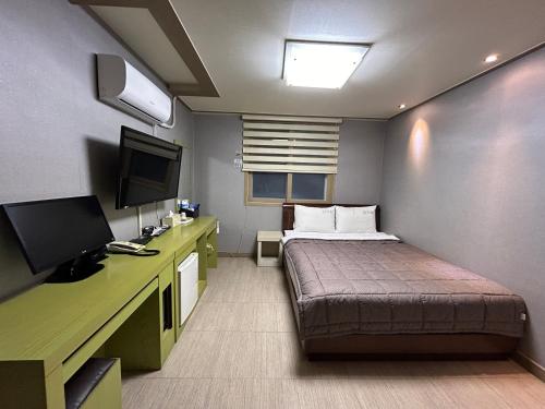 a small room with a bed and a television at Vision motel in Geoje 