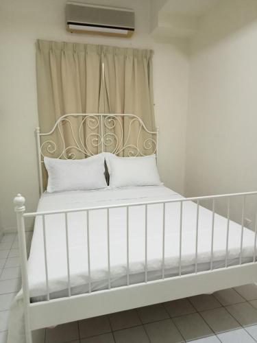1 cama blanca con almohadas blancas en una habitación en Lestari Seaview Homestay en Port Dickson