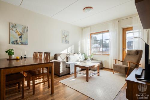 sala de estar con mesa y sofá en Holiday in Lapland - Alppilevi 1 B1, en Kittilä
