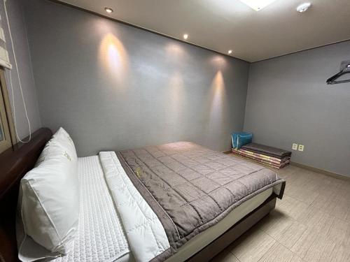 1 dormitorio con 1 cama con pared gris en Vision motel en Geoje 