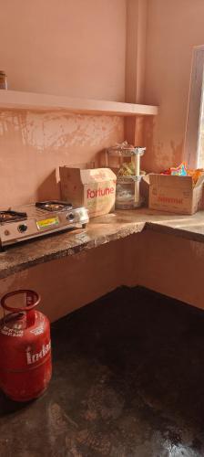 um balcão de cozinha com caixas e uma panela vermelha. em Saanidhya hostels em Mukteshwar