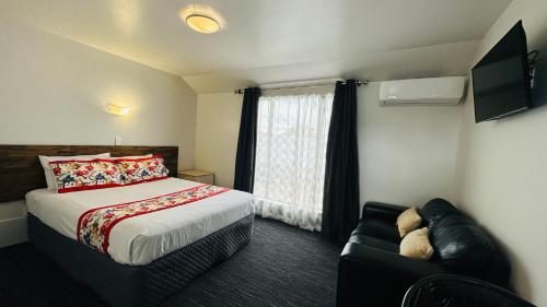 1 dormitorio con cama, sofá y ventana en Samhil Motor Lodge en Christchurch