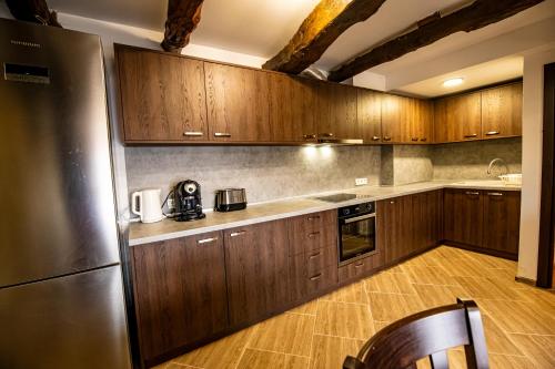 La cuisine est équipée d'armoires en bois et d'un réfrigérateur en acier inoxydable. dans l'établissement Apriltsi Hills, à Apriltsi