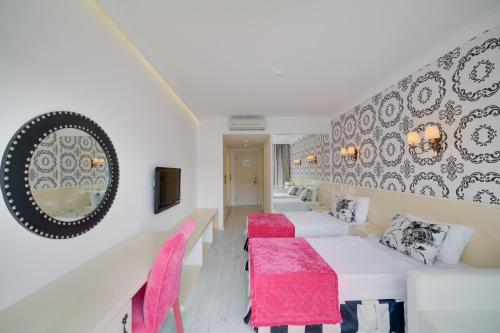 um quarto com duas camas e cadeiras cor-de-rosa em Ladonia Hotels Mio Bianco em Akiarlar