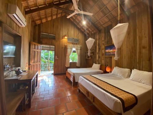 a bedroom with two beds and a bathroom with a sink at Ancarine Beach Resort in Phú Quốc