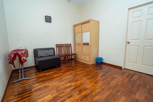 a room with a chair and a cabinet and wooden floors at GLYSM Tambun Stay in Ipoh
