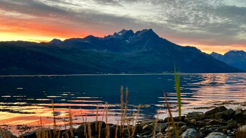a sunset over a lake with mountains in the background at Artic Dream in Gratangen