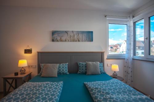 a bedroom with a blue bed and two windows at Lago Gricio in Langenargen