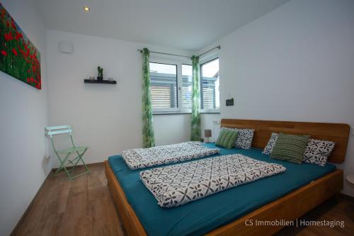 - une chambre avec un lit doté de draps bleus et une fenêtre dans l'établissement Lago Rosso, à Langenargen