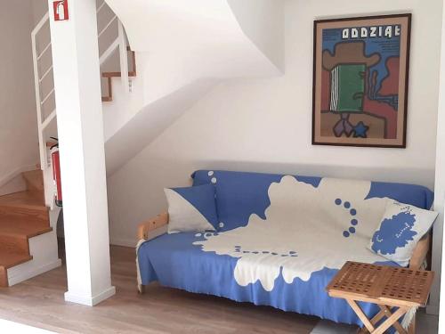 Sofá azul en una habitación con escalera en River & Beach Apartment near Lisbon, en Trafaria