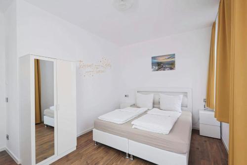 a white bedroom with a bed and a mirror at Ferienqartier- Forsthaus in Bad Gottleuba