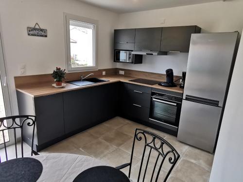 La cuisine est équipée d'un évier, d'un réfrigérateur et de chaises. dans l'établissement Alizes ABBA - 500m de la plage, à Saint-Vincent-sur-Jard