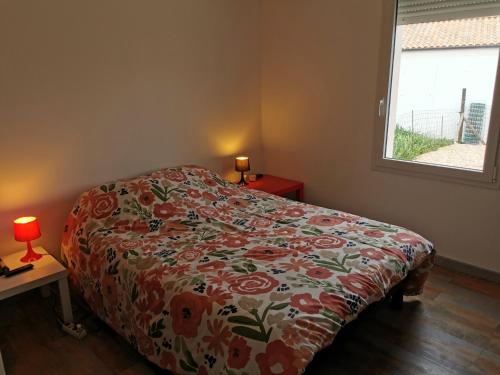 - une chambre avec un lit doté d'un couvre-lit floral et d'une fenêtre dans l'établissement Alizes ABBA - 500m de la plage, à Saint-Vincent-sur-Jard