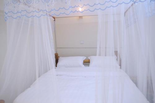 a bedroom with two beds with white curtains at Kabalega Diner Limited in Nalakonge