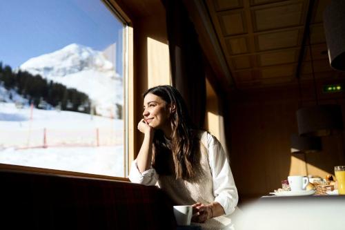 Una donna seduta su un treno che guarda fuori da una finestra di Hotel Steffisalp a Warth am Arlberg